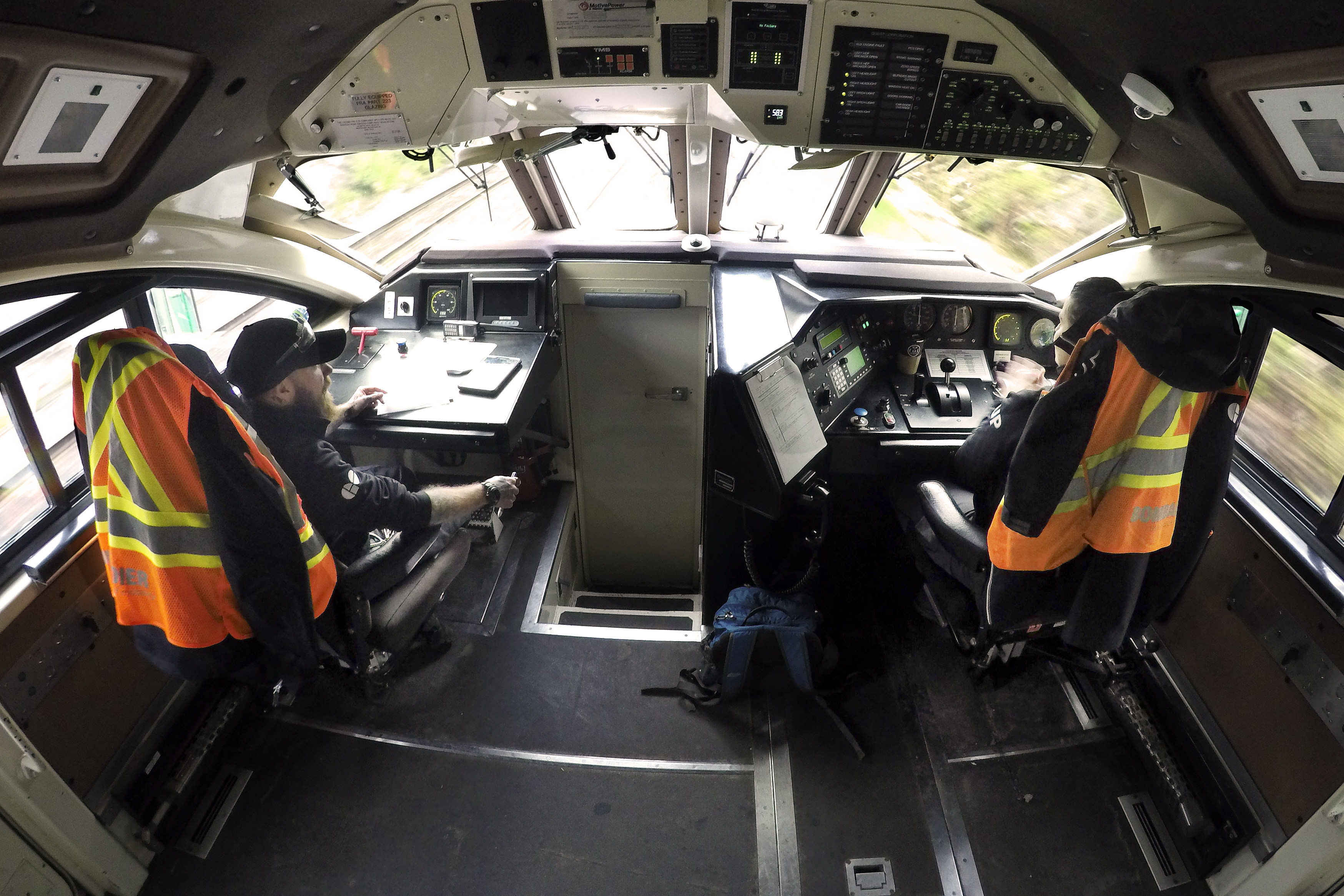 An inside view of the GO locomotive cab with two operators sitting in the chairs.