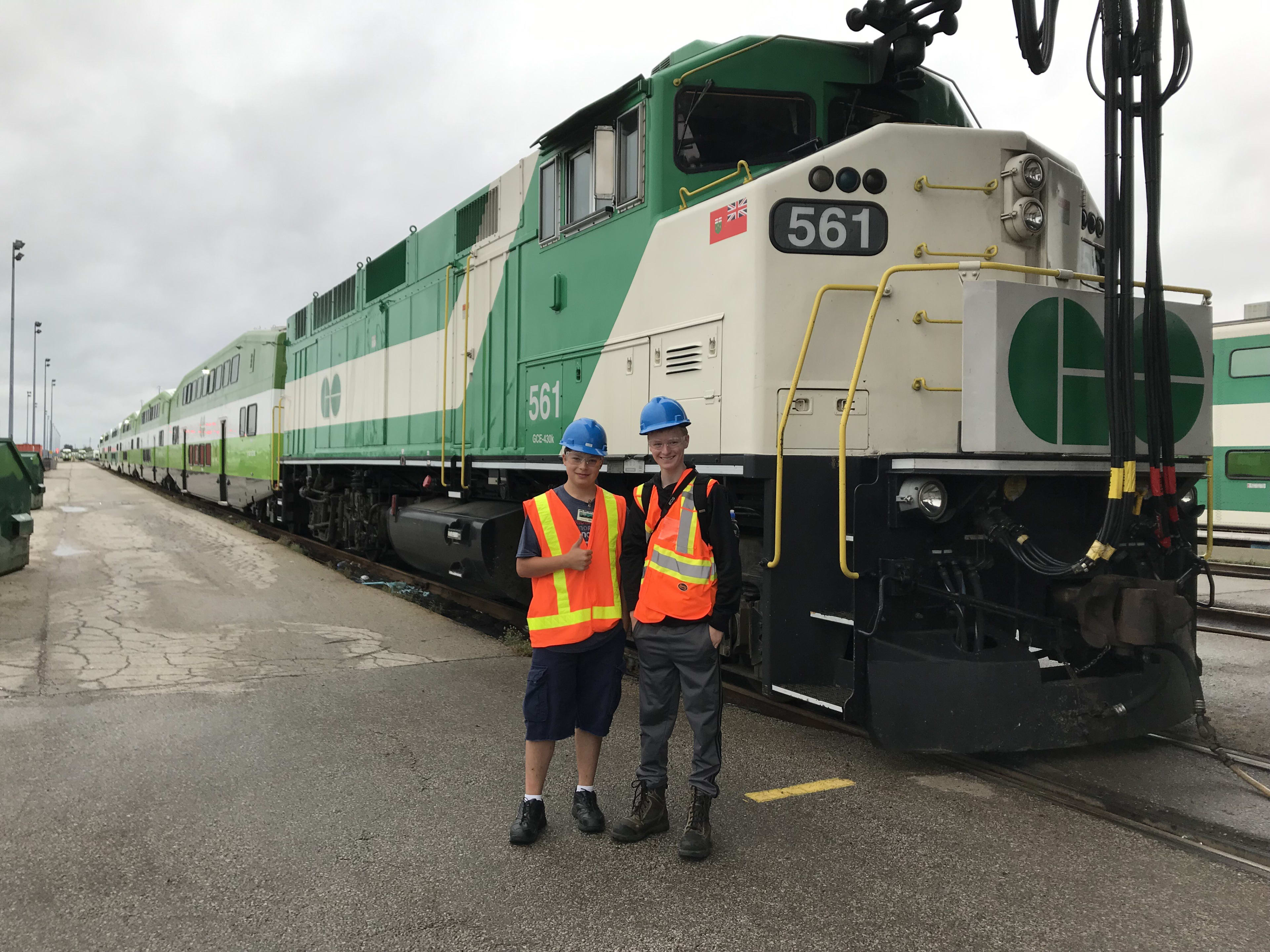 The two teens stand next to a large GO train while on a recent visit to the Wilowbrook facility.