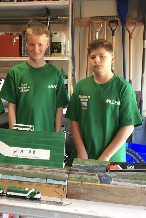 The two teens pose in front a model GO train set.