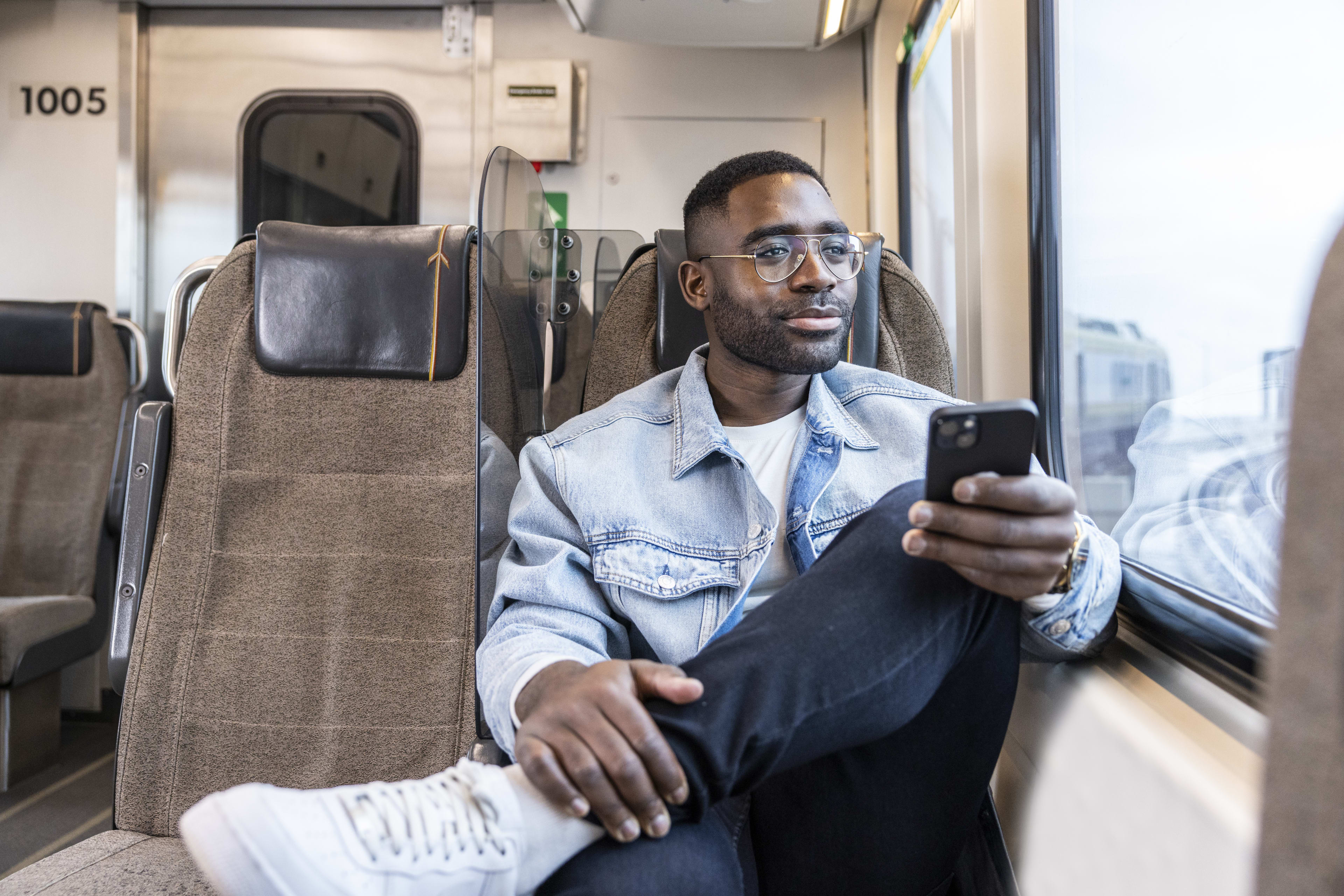 Man sitting on board UP Express looking out the window with phone in his hand