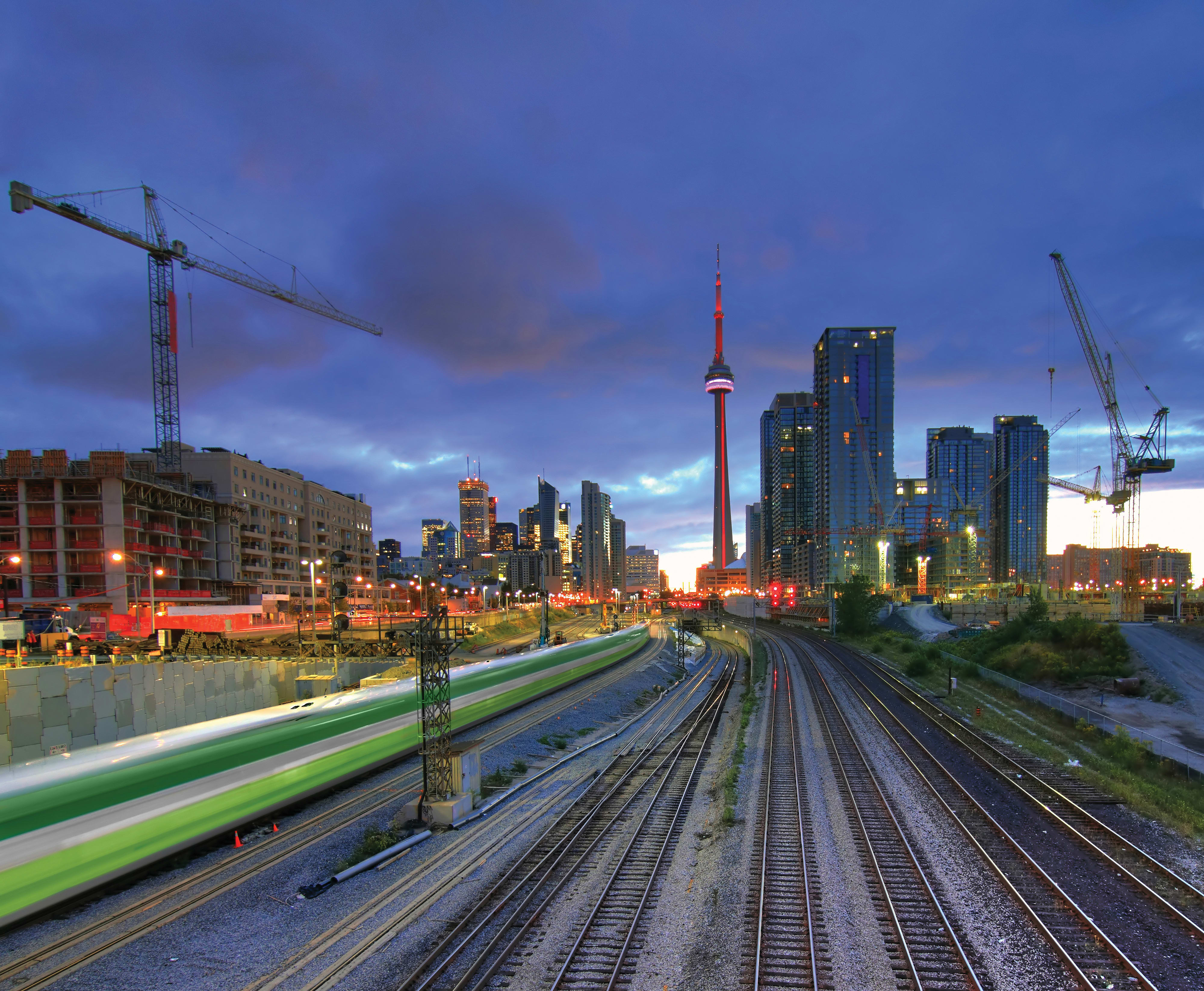 GO Train at dusk in downtown Toronto with CN Tower in the background