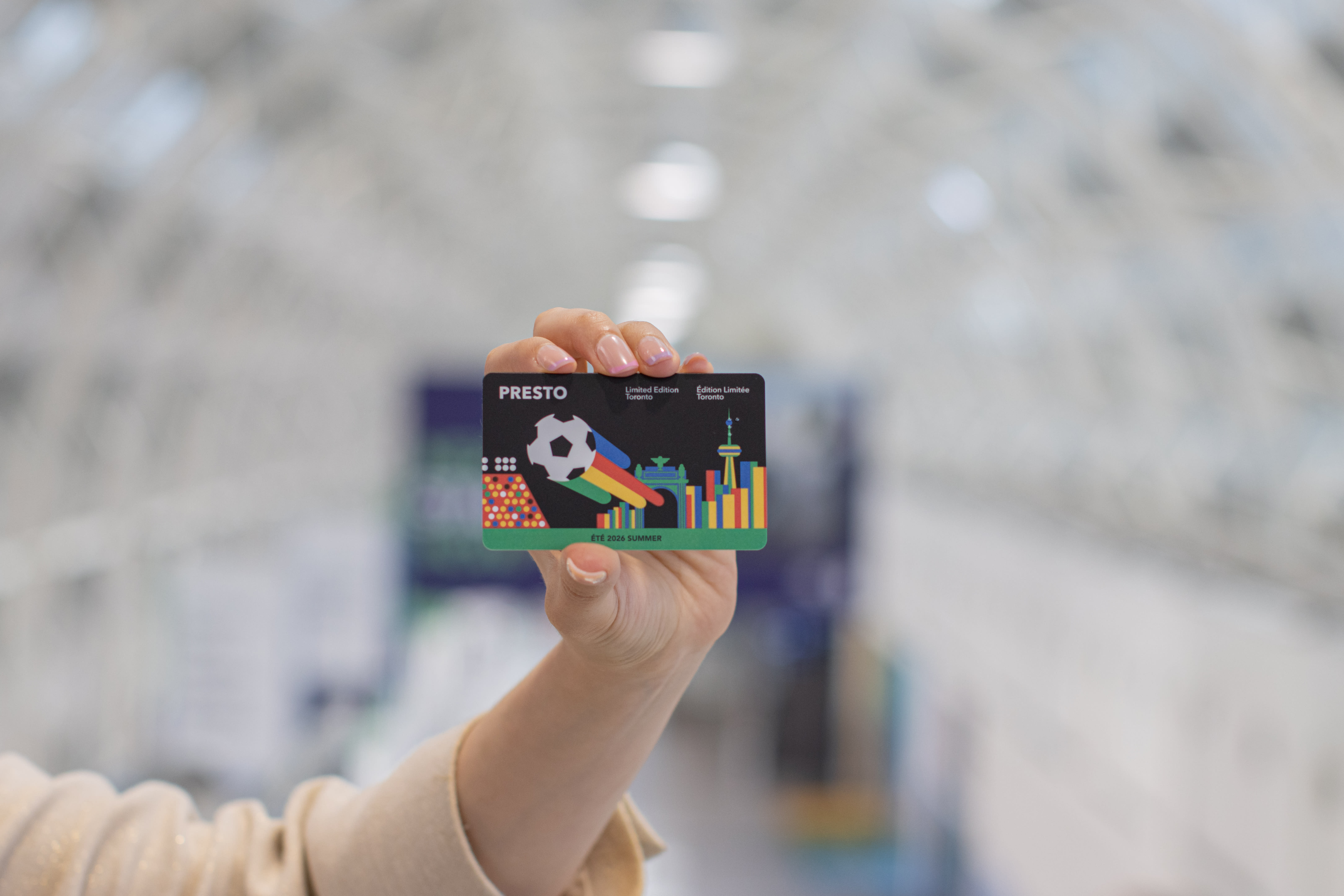Image of a payment card being held in a person's hand with a light open hall in the background.
