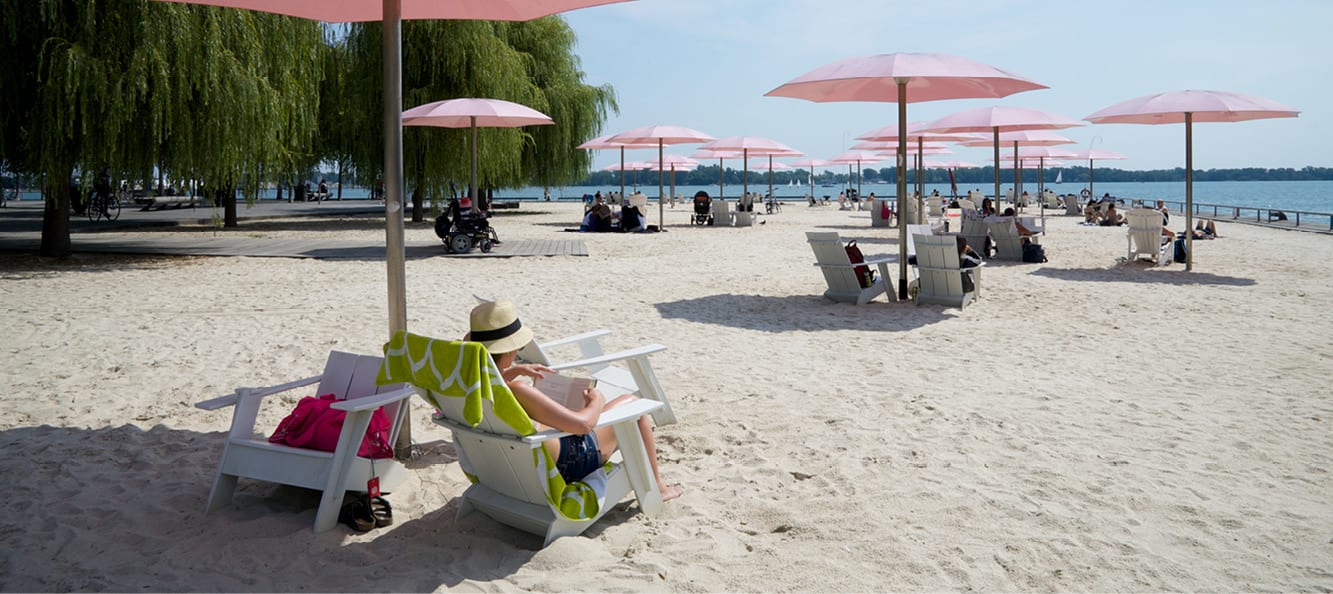 A person sitting in chairs on a beach with umbrellas