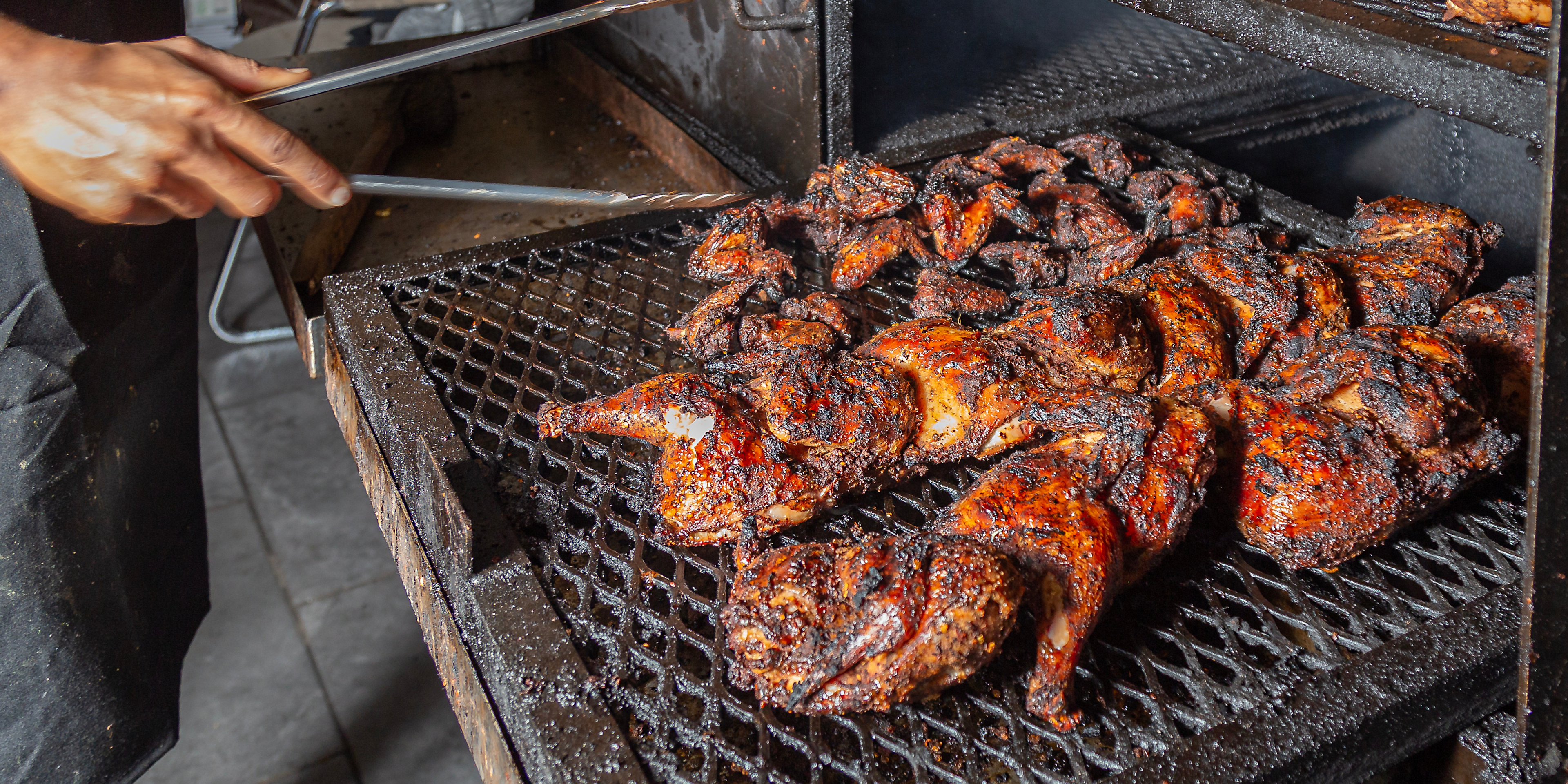 Jerk chicken being grilled on a barbeque