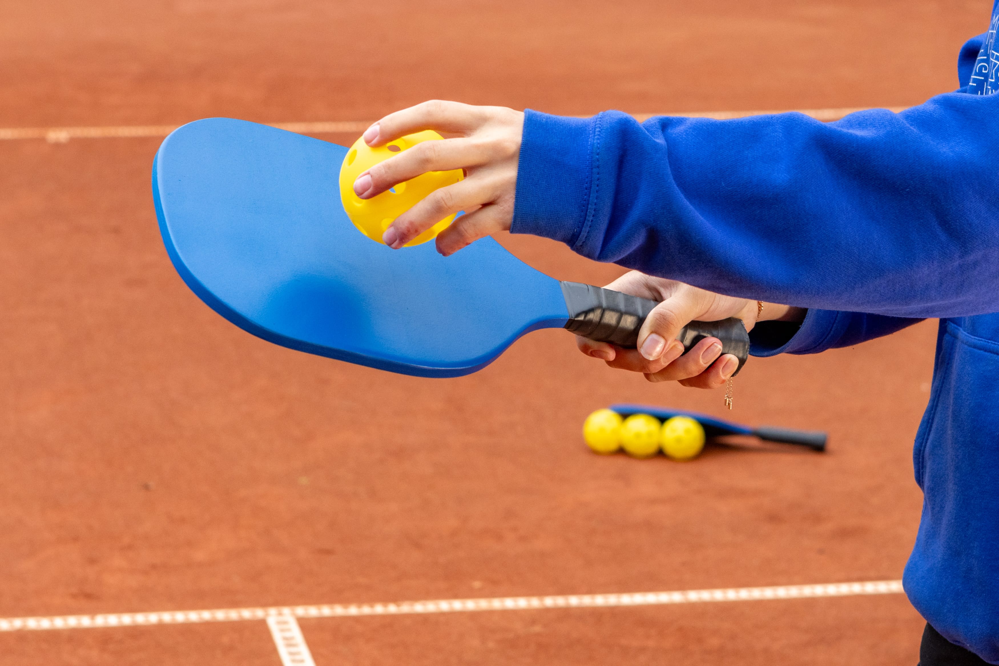 Person holding pickleball racquet and ball