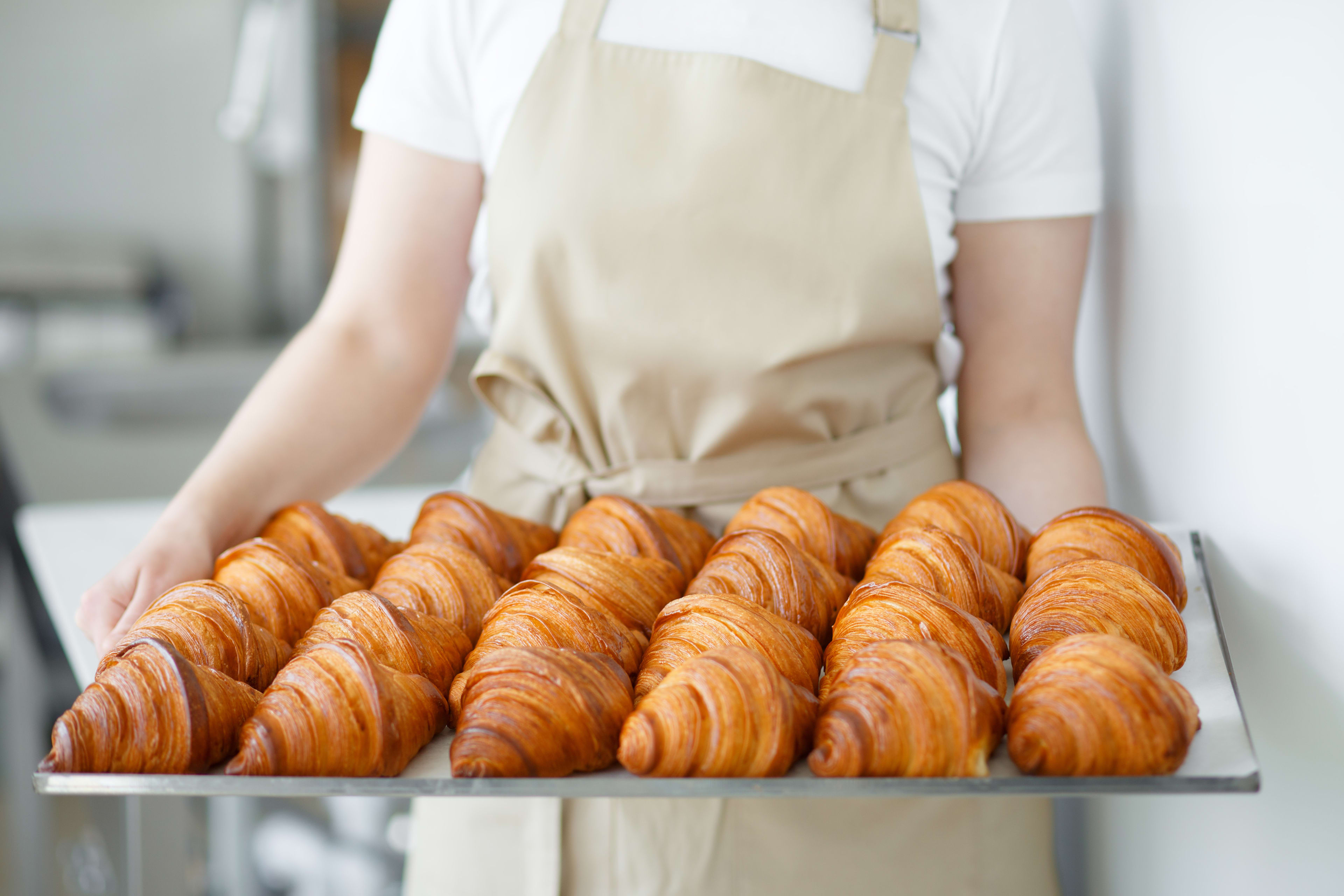 Person holding tray full of butter croissants