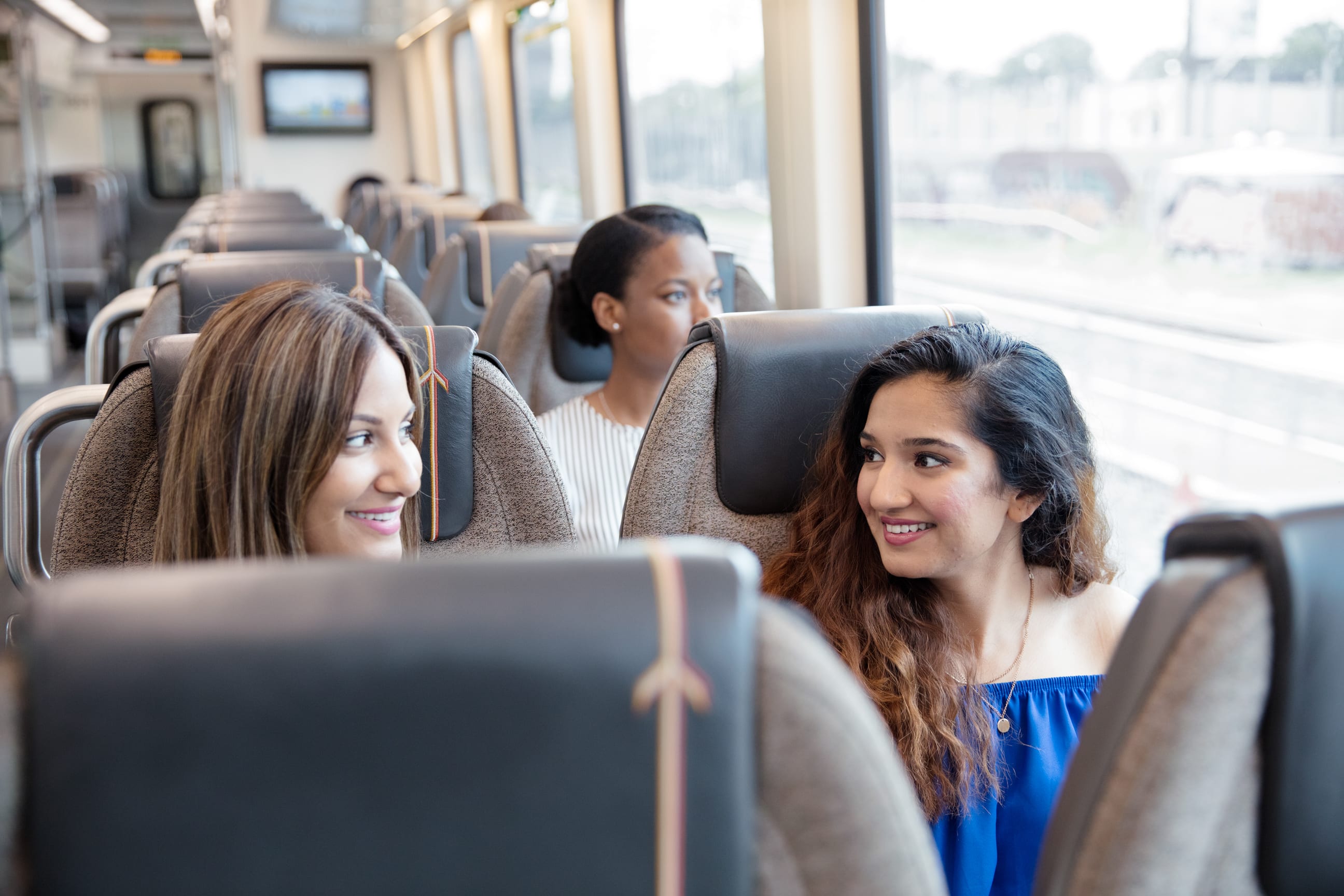Two women onboard UP Express speaking to one another.