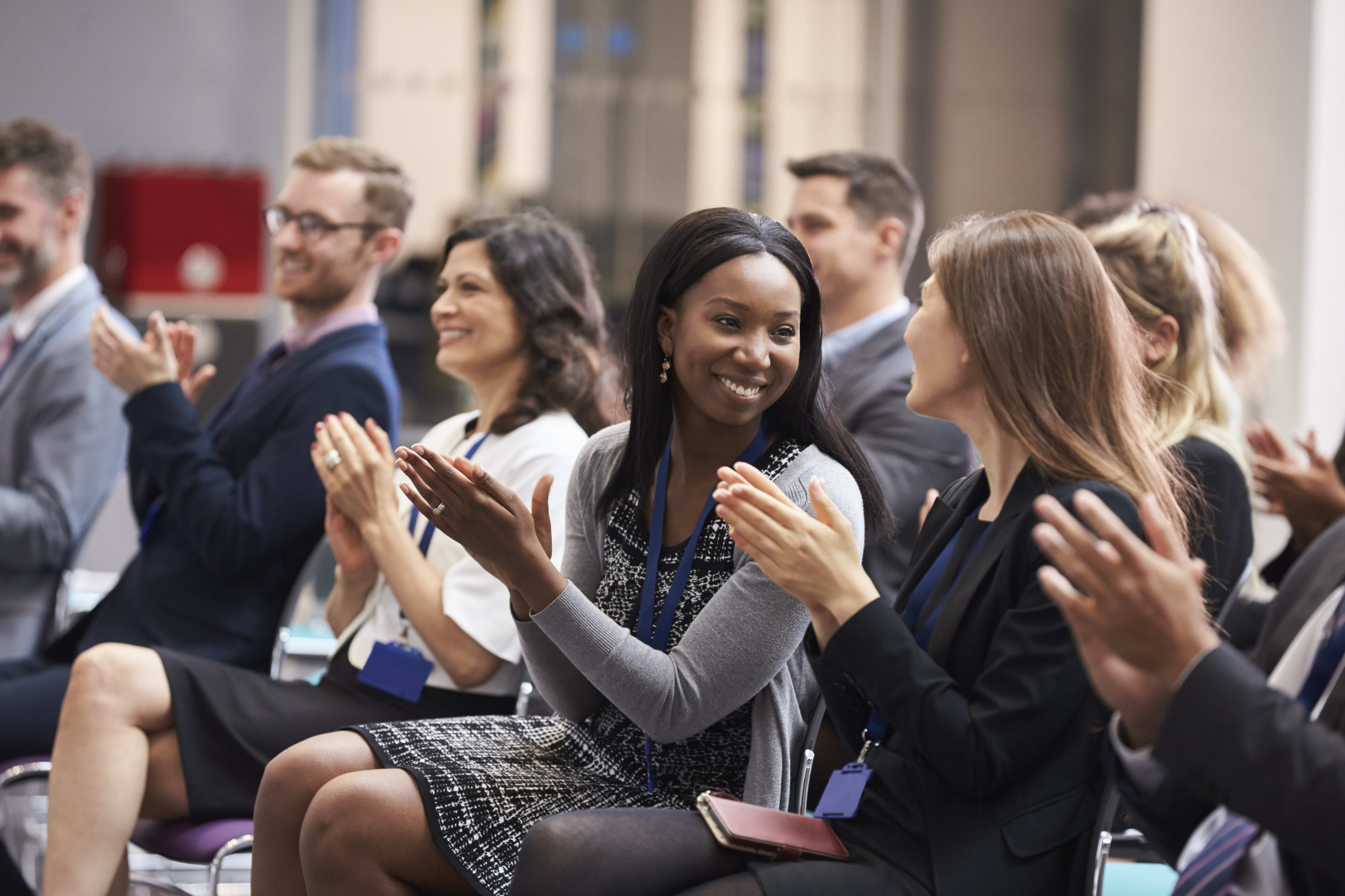 Two people staring at each other clapping around a larger group of people