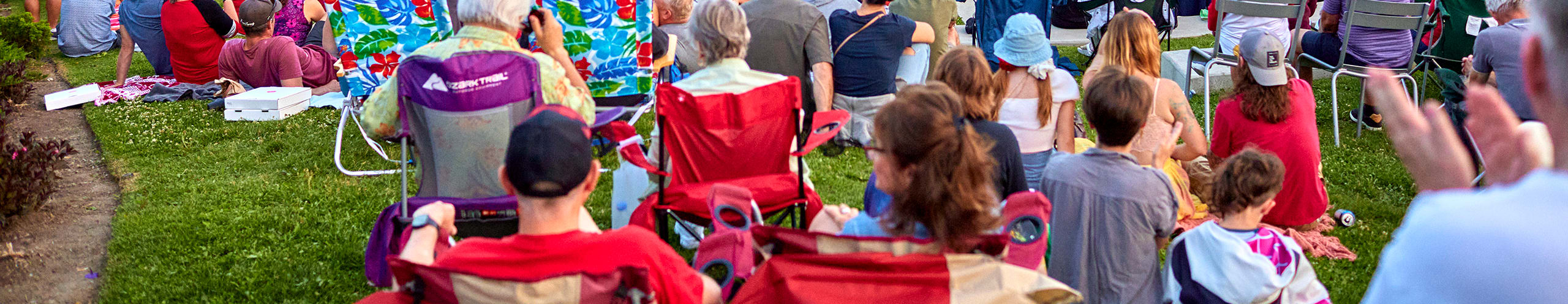 crowd sitting in grass on sunny summer day