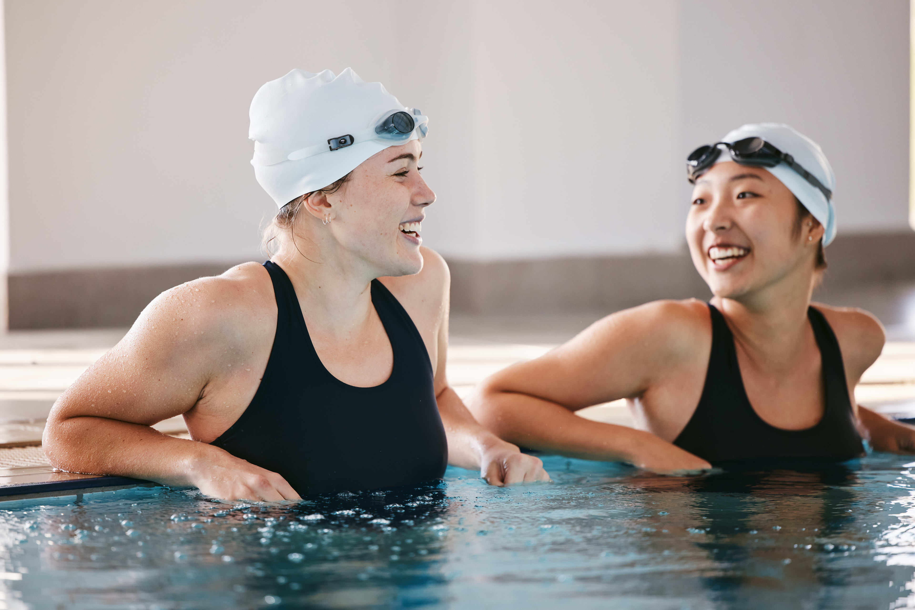 Two girls standing in a swimming pool talking