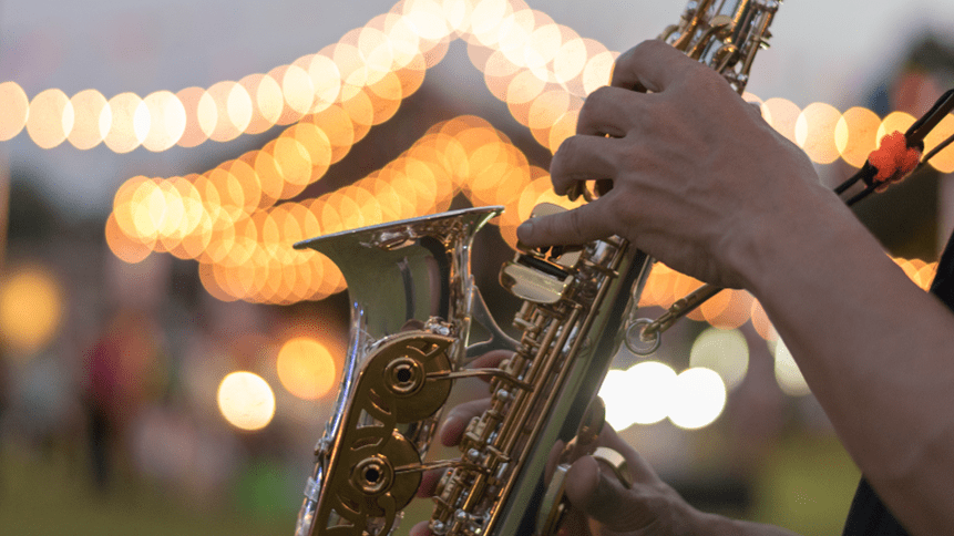 Person playing saxophone at dusk at a music festival