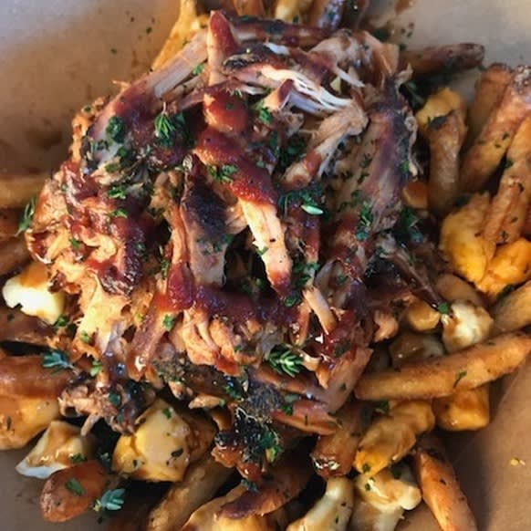 A poutine in a paper box - fries with cheese covered with jerk chicken shredded with gravy