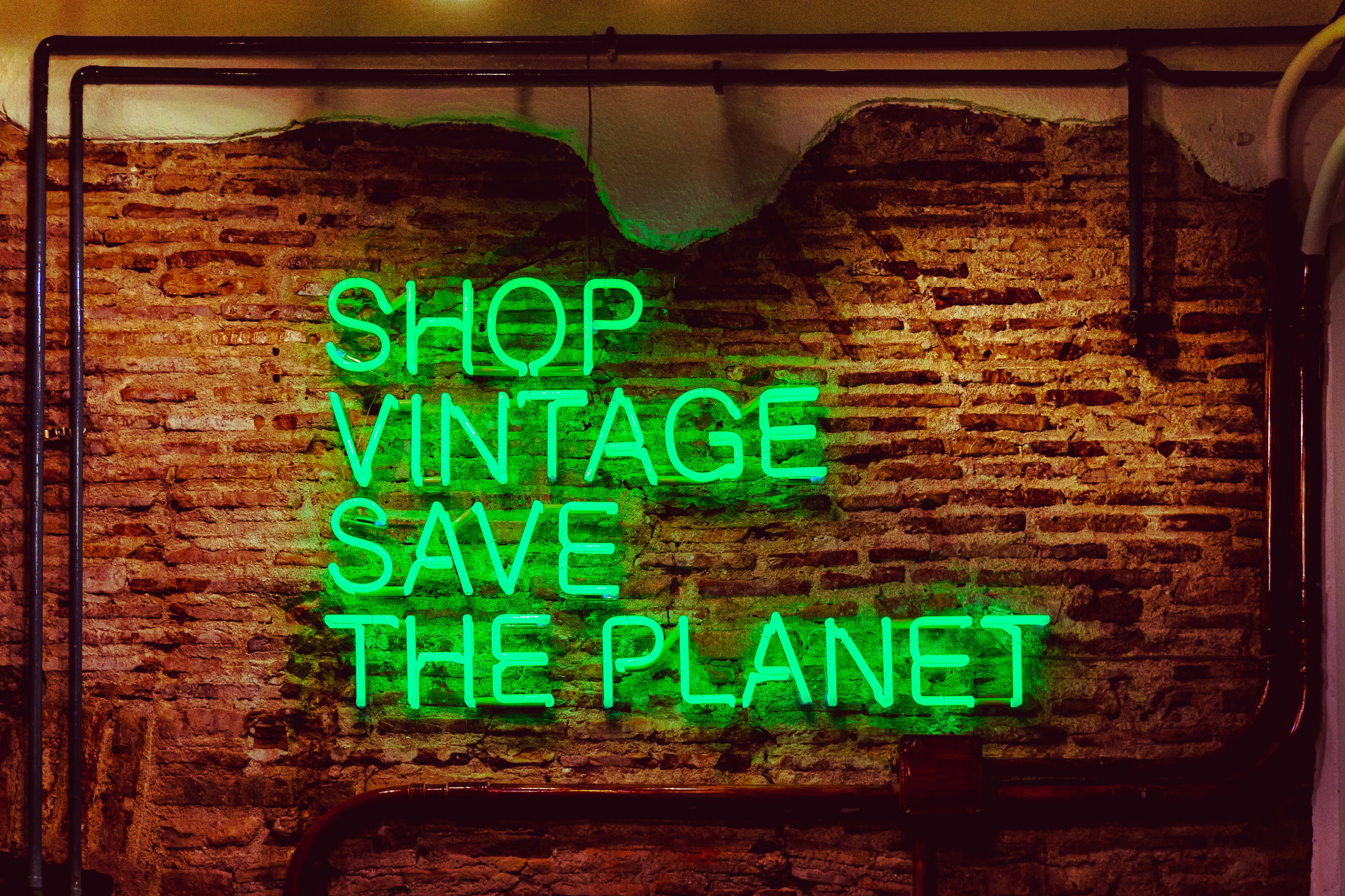 Green neon sign that says "Shop vintage save the planet"