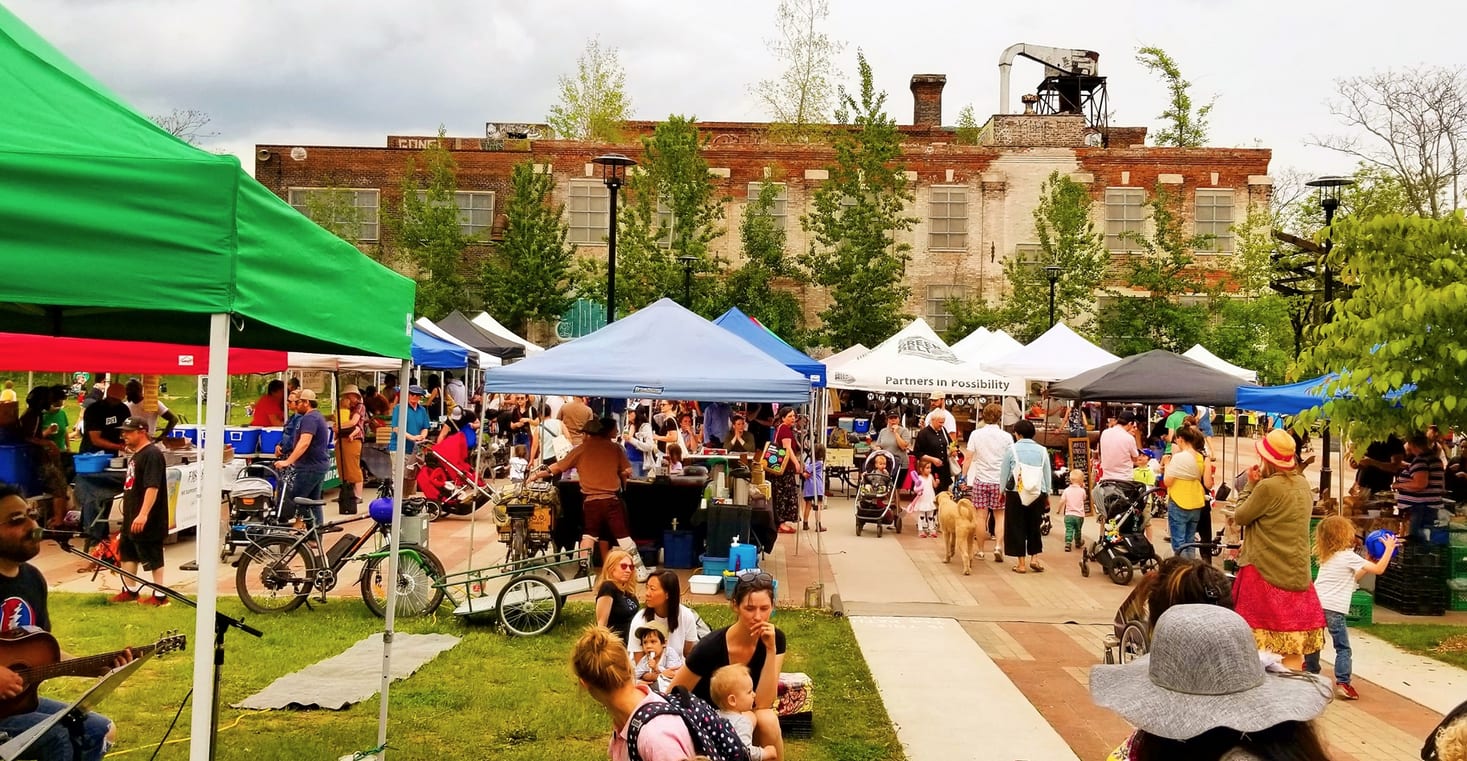 Busy farmer's market with many vendors underneath tents