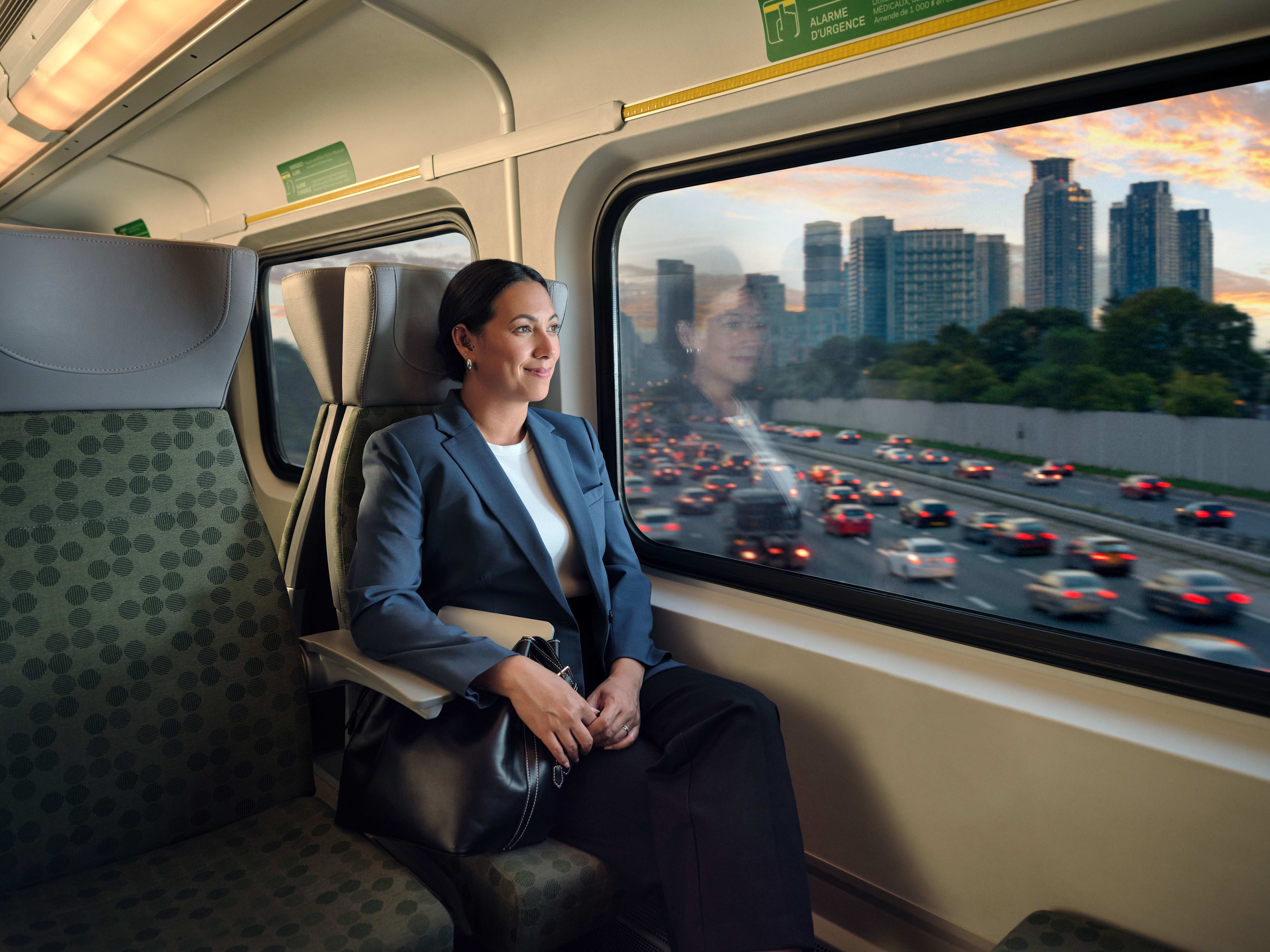 Woman sitting on GO train commuting home, passing by traffic