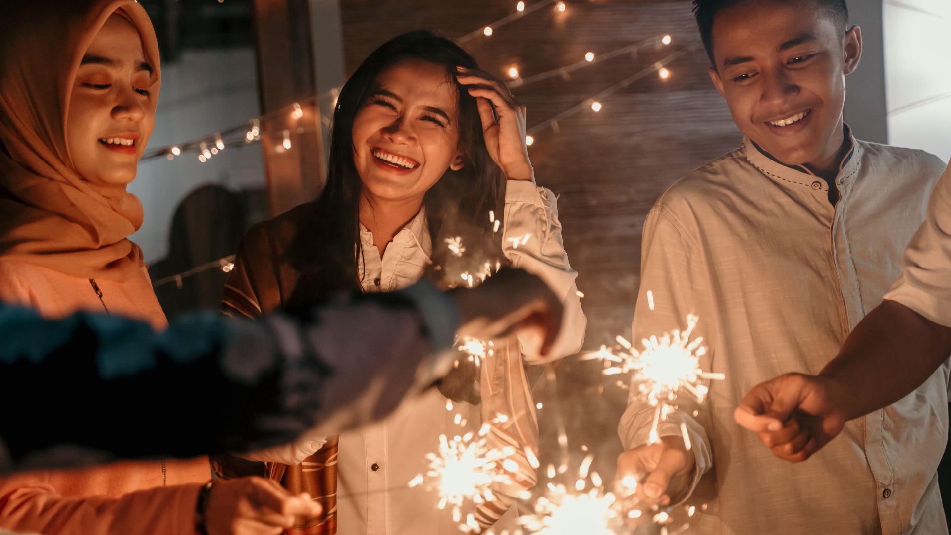 two women and man holding sparklers celebrating Eid.