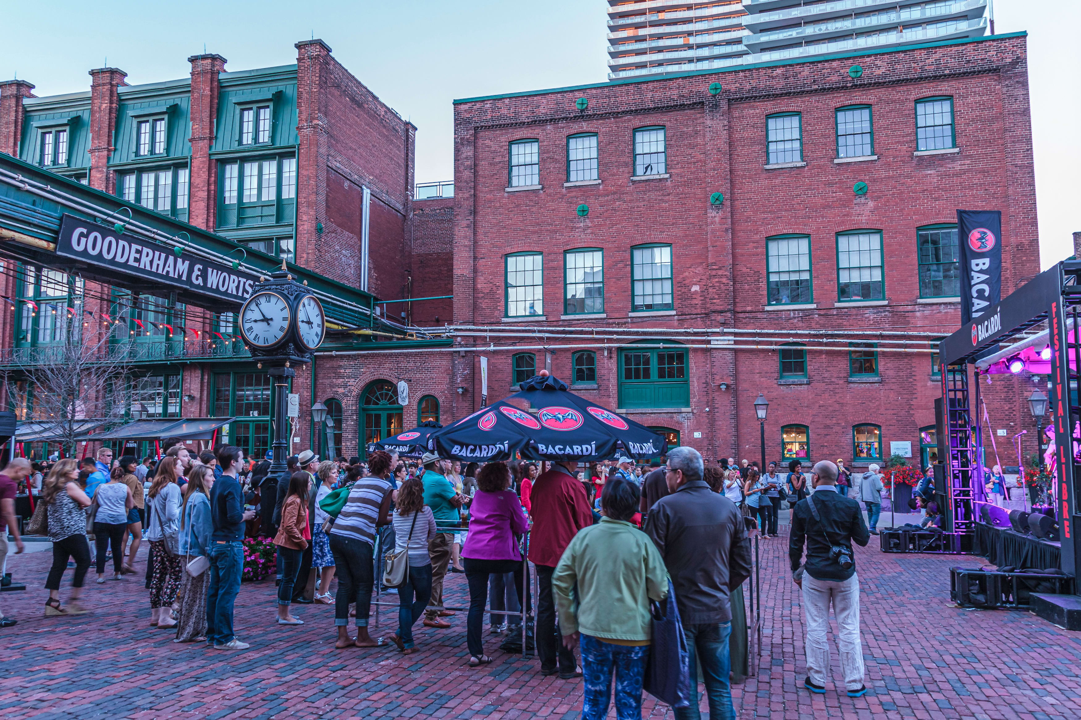 Toronto's Distillery District with crowds exploring around red brick buildings.