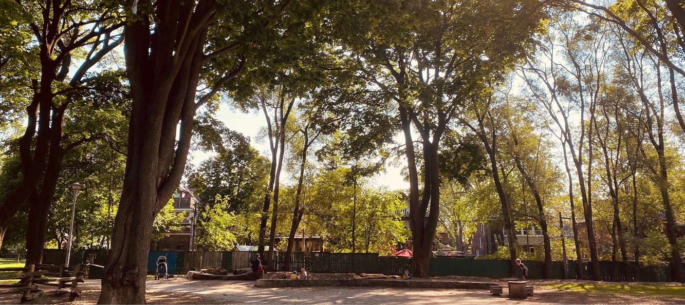 Dufferin Grove Park walkway with a sand area with two kids playing in front of a fence