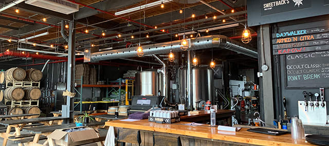 Brewery storefront with picnic tables on the left and menu on the right