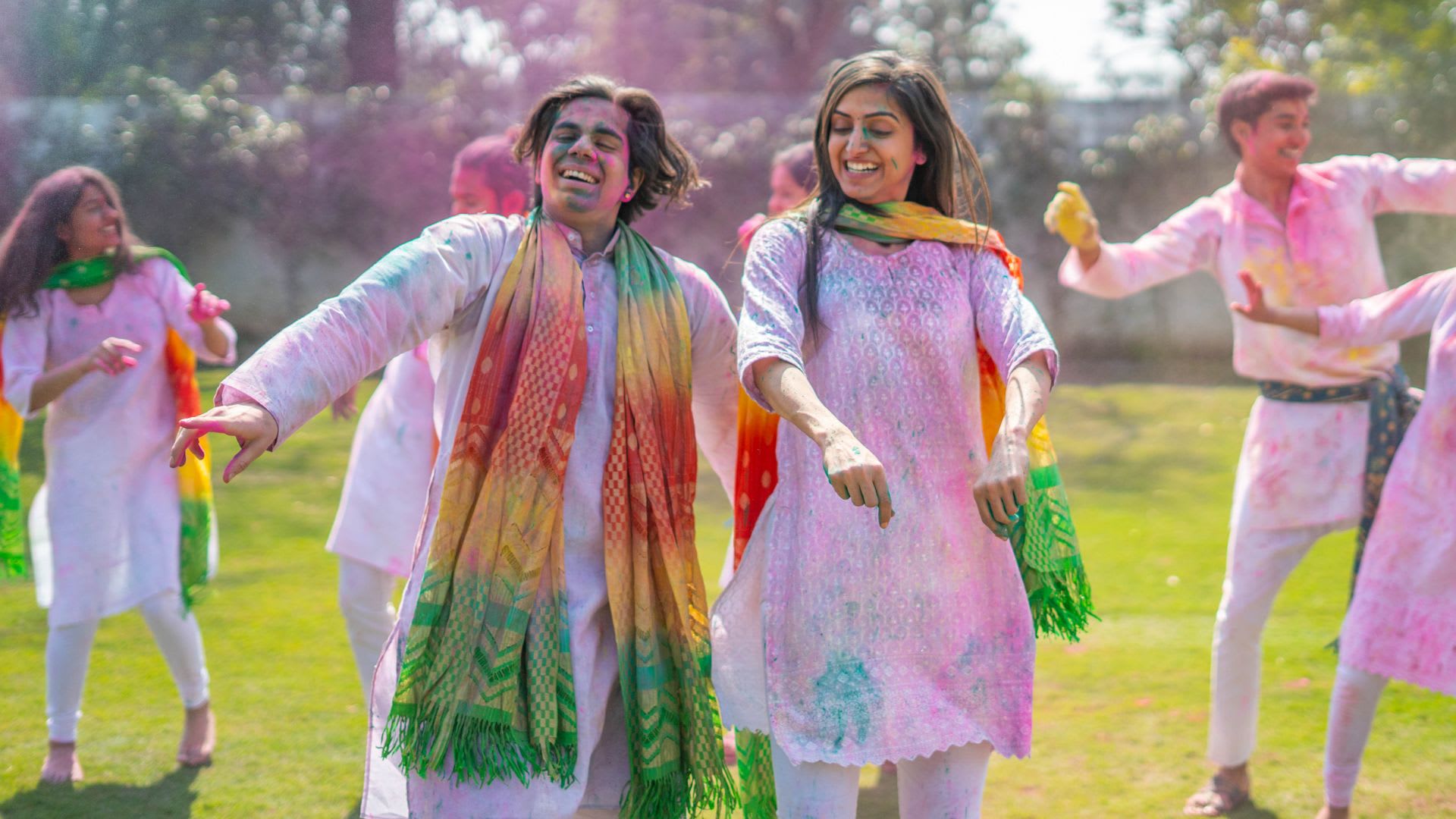 A man and women celebrating Holi by throwing colourful powders.