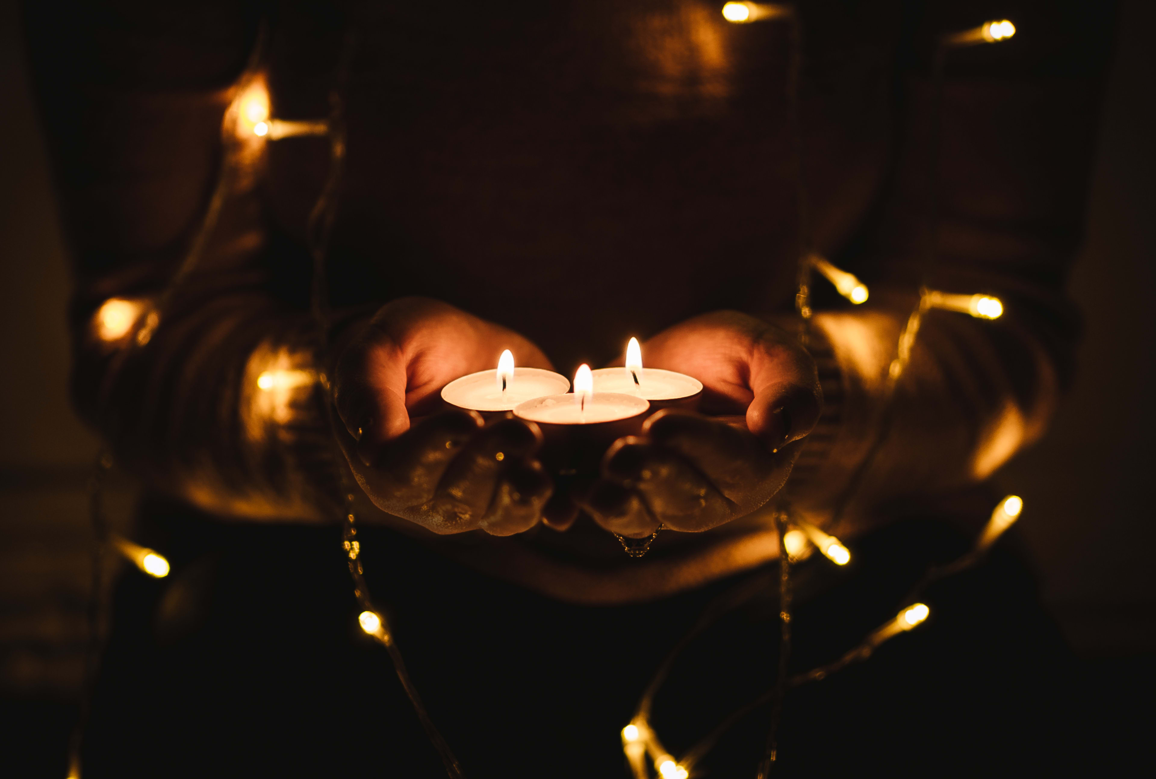 Person holding candles lit with decorated with string lights