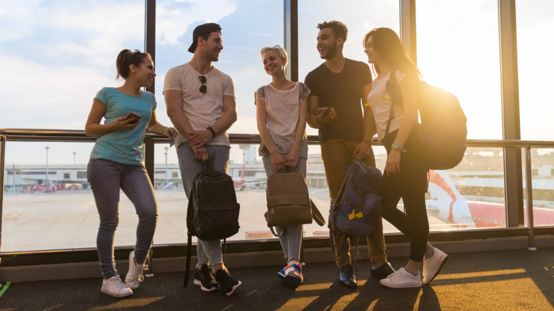 Group of five travelers standing together at an airport