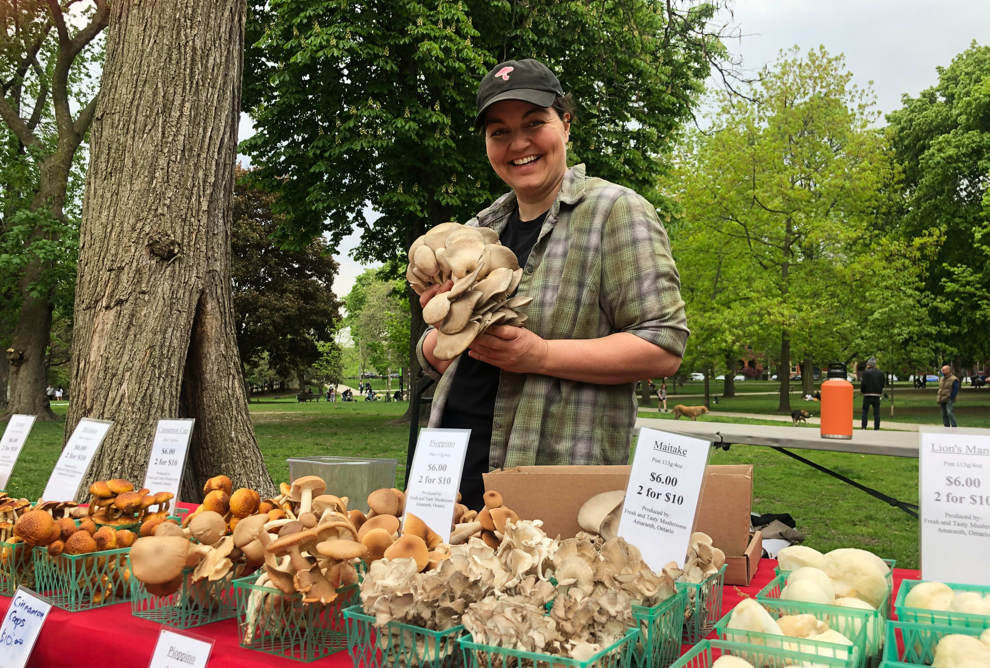 Vendor standing in front of table with mushrooms holding a mushroom