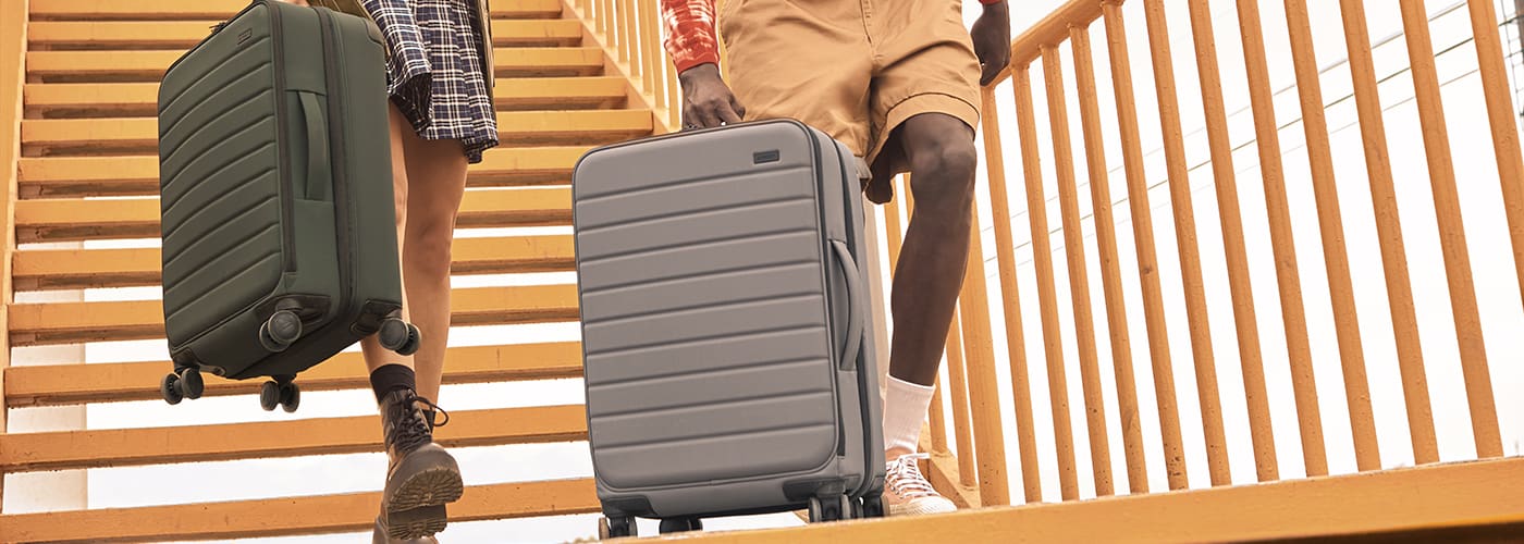 Man pushing luggage while wearing a face covering