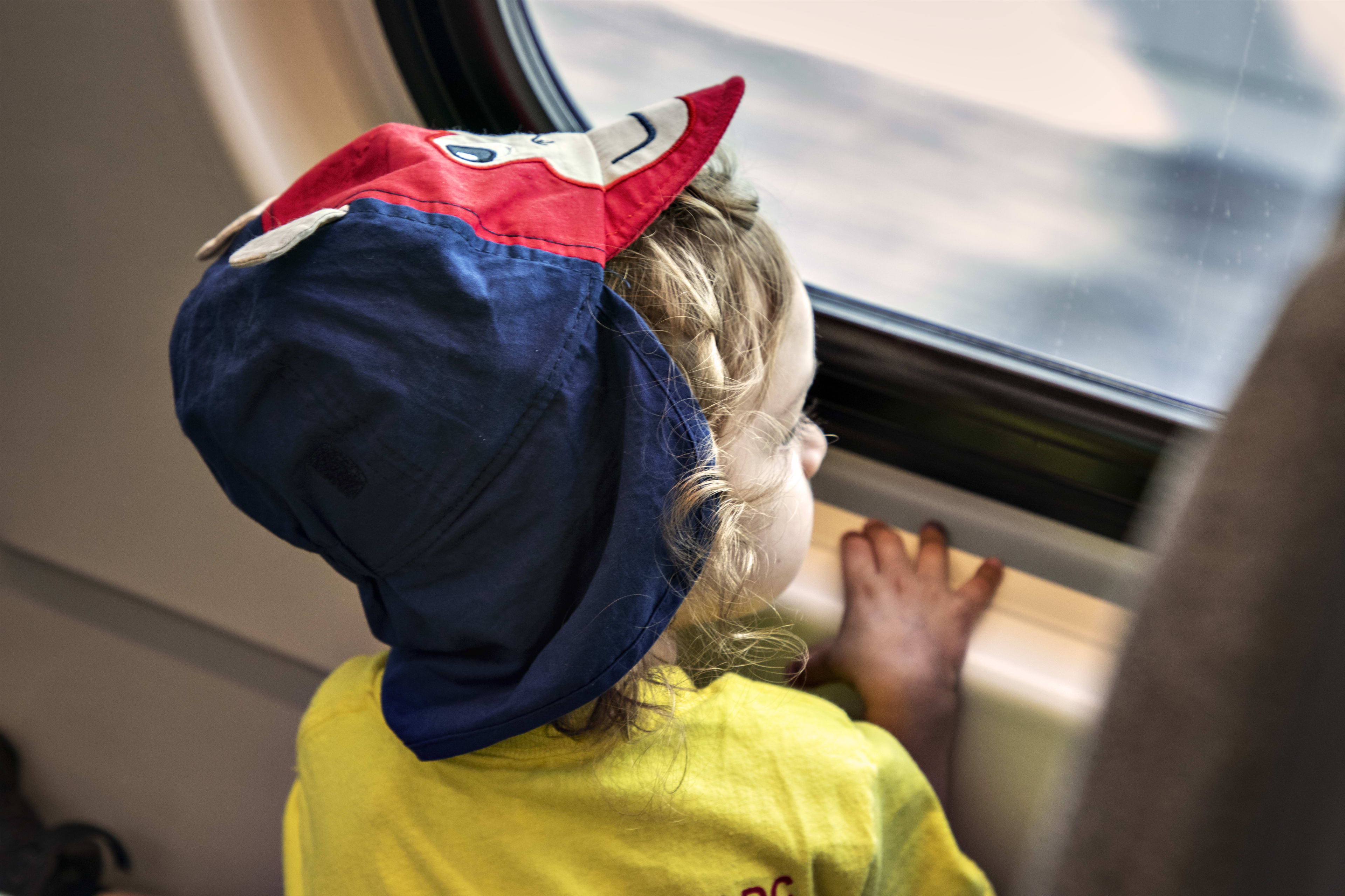 A young child looks out of a train window.