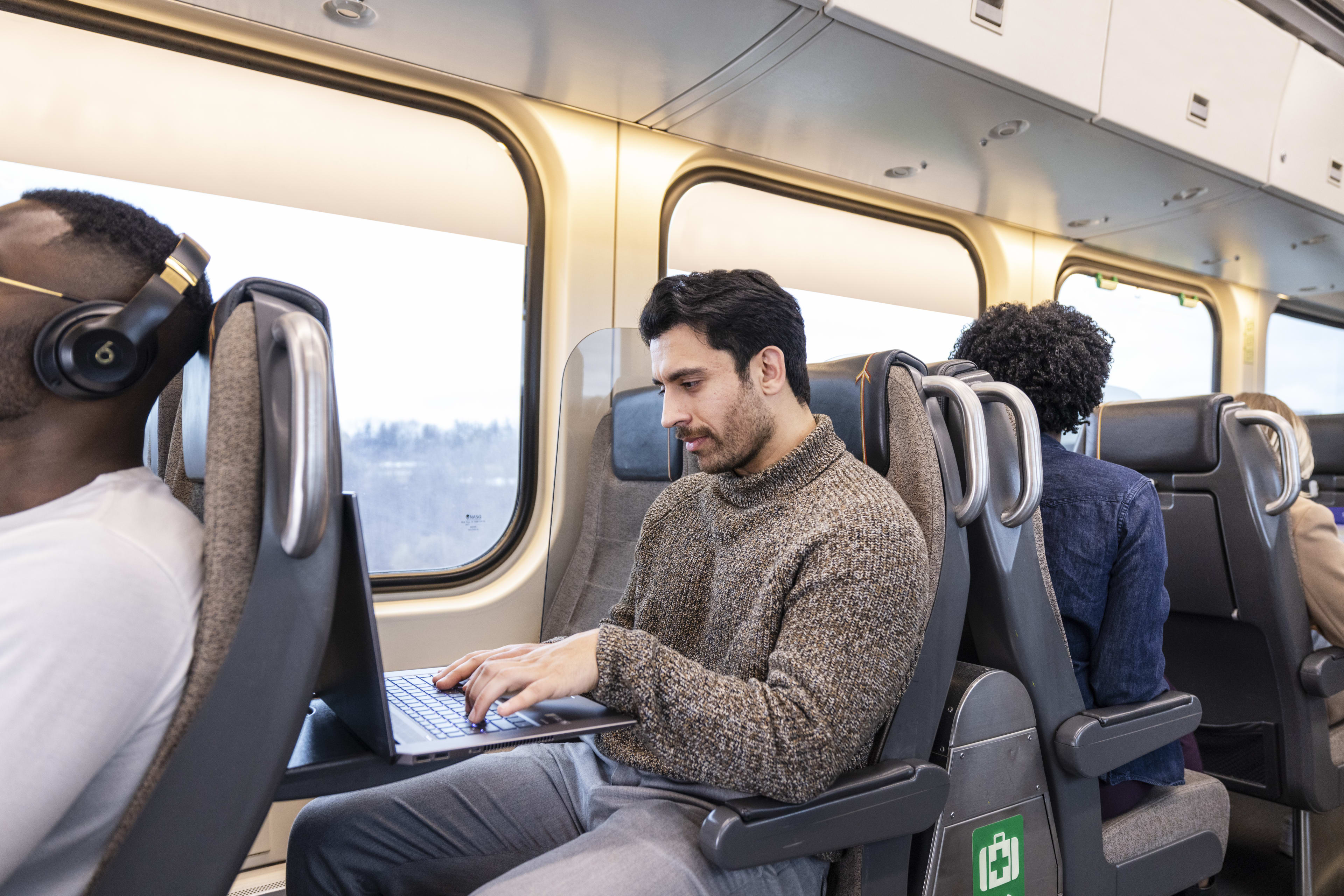 Man onboard UP Express train working on this laptop