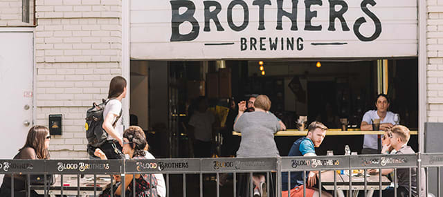 Groups of people sitting outside brewery dining and talking to each other.