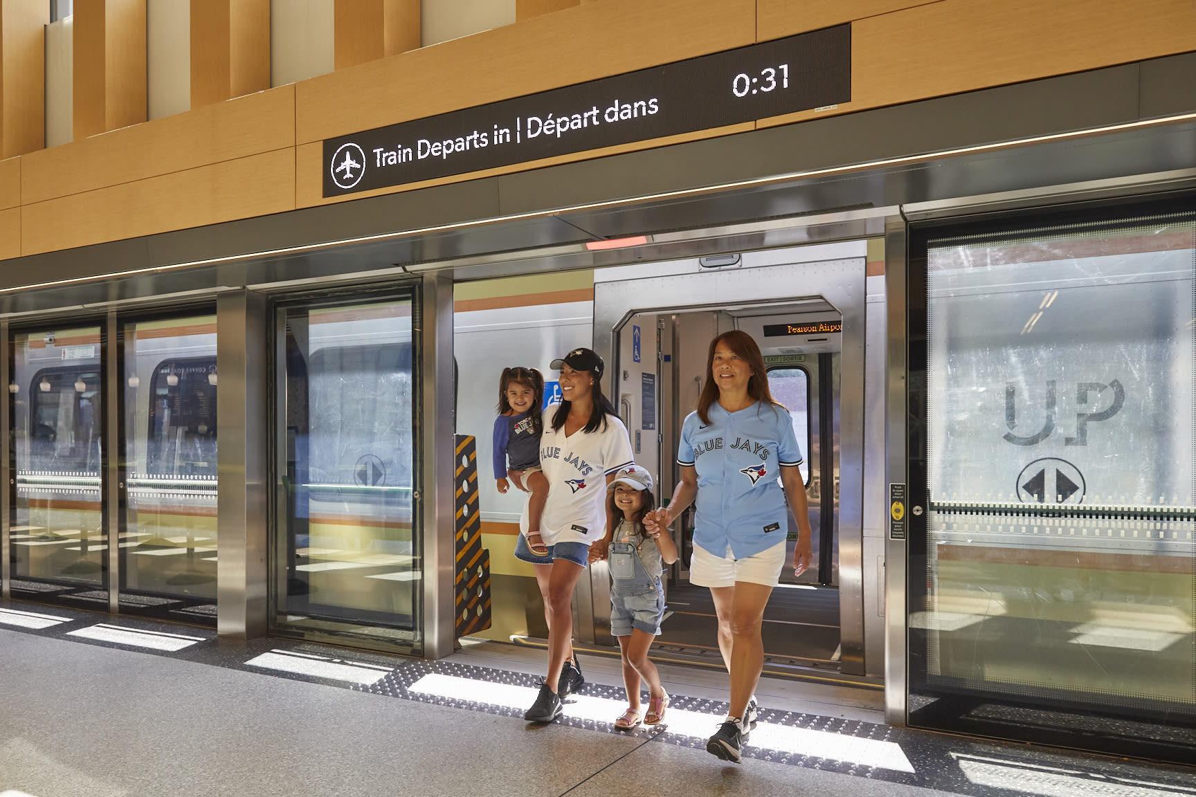 Mom, grandmother and two children walking off of UP train at Union Station in Blue Jays jerseys.